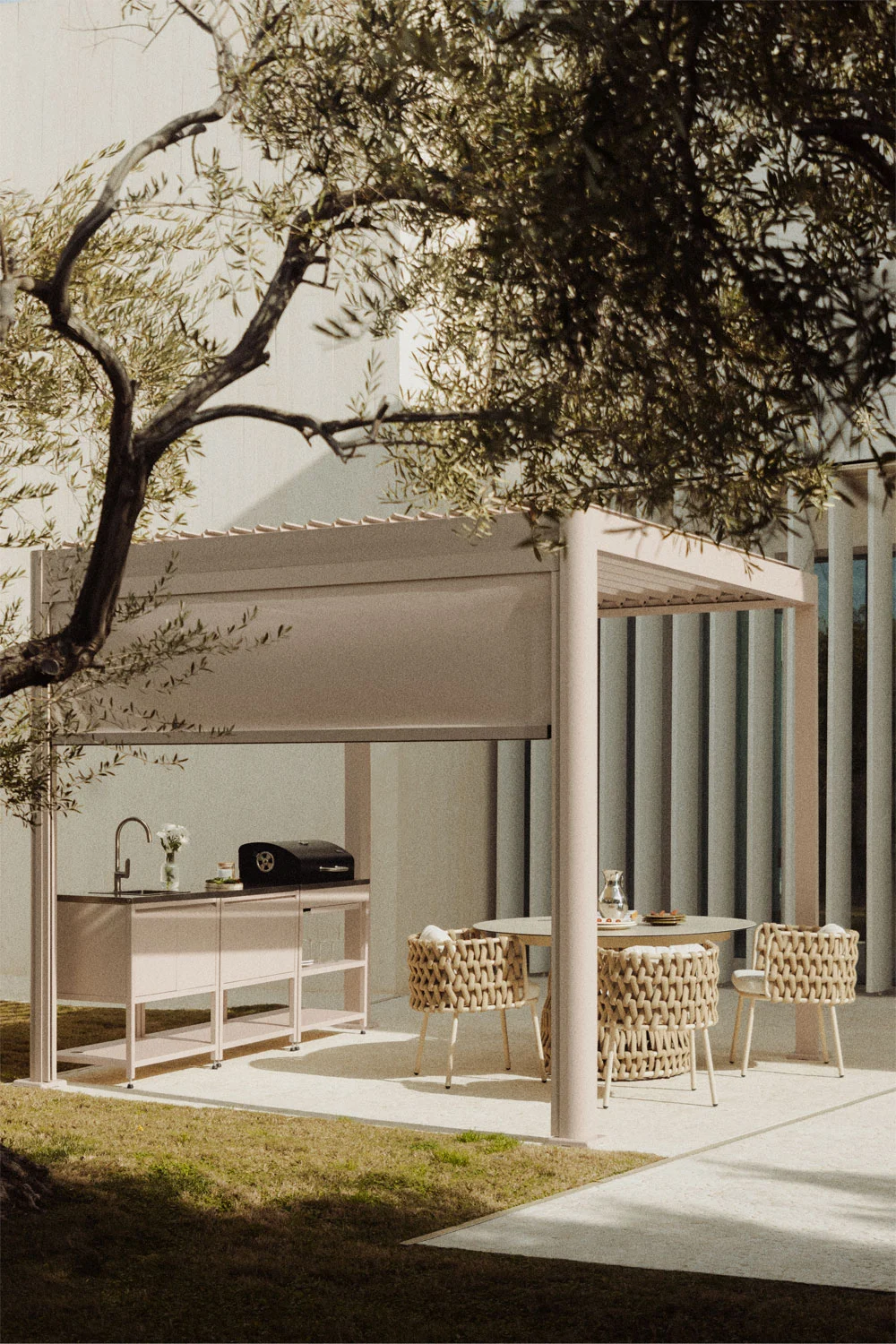 Pale aluminium bioclimatic pergola with side screen, outdoor kitchen and dining setting