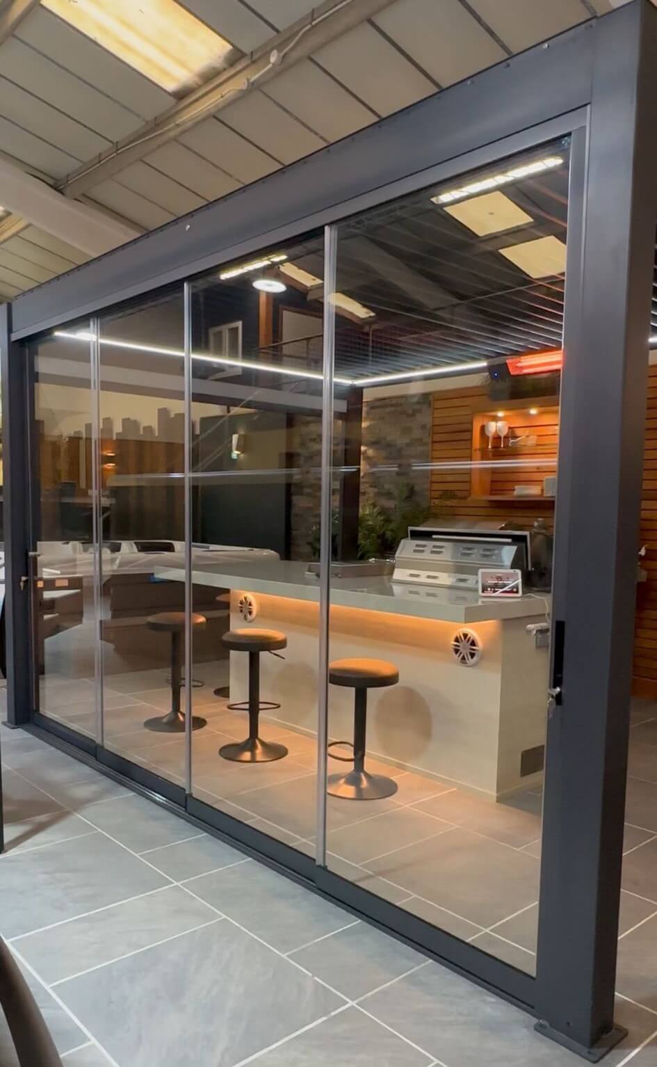 Frameless-style sliding glass panels enclosing one side of a pergola